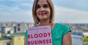 Bettina Steinbrugger zeigt eine Ausgabe ihres Buches "Bloody Business"